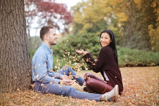 Happy couple scattering leaves in park - How to flirt with a guy 