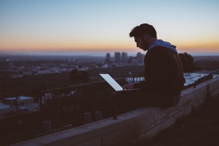 man sitting with laptop on his lap