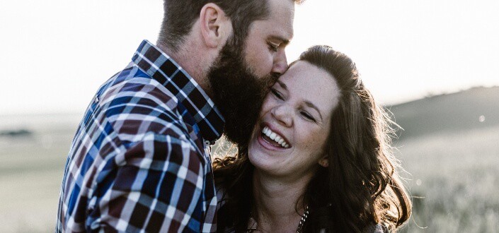 man kissing woman in a field