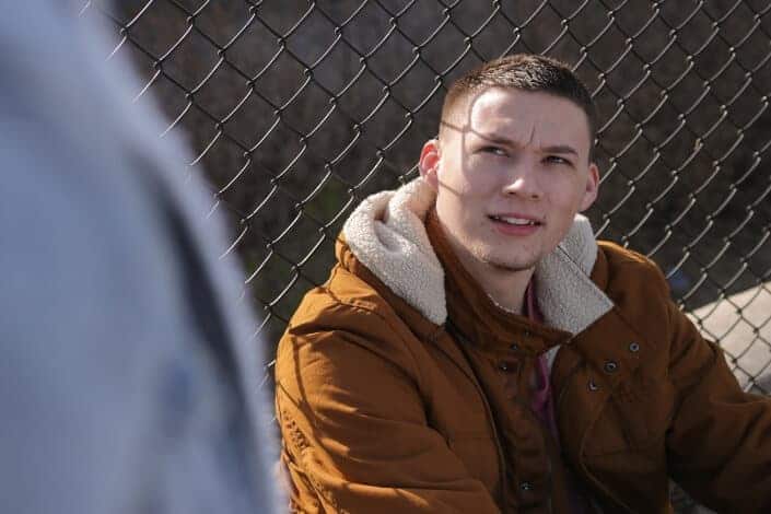 man leaning on fence looking up