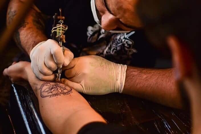 man doing tattoo art to someone