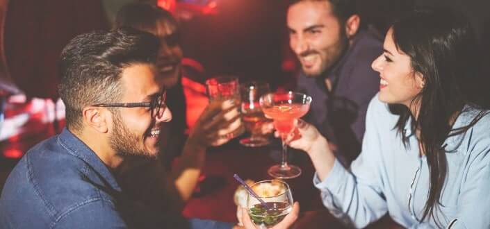 friends drinking and toasting cocktails in a bar