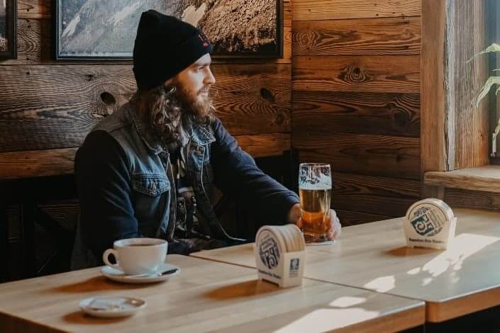 man staring at the window holding beer