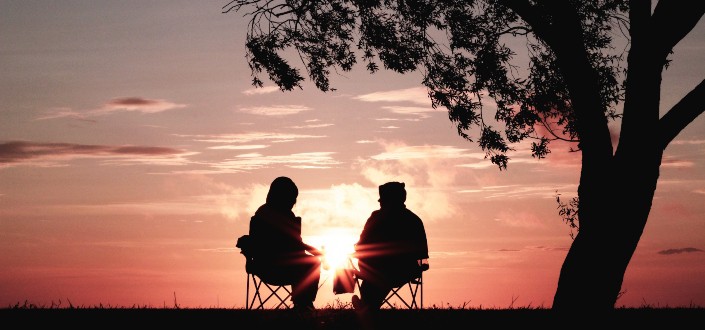 Couple sitting on folding chairs under a tree