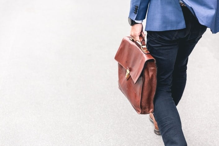 Guy walking out of office carrying leather suitcase