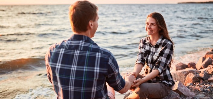 Couple Wearing Matching Plaid Shirts Facing Each Other on a Beach