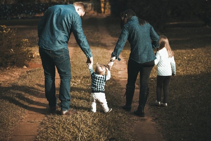 Couple walking their son with a little girl beside them.