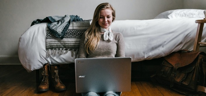 woman sitting on a bedroom floor using laptop