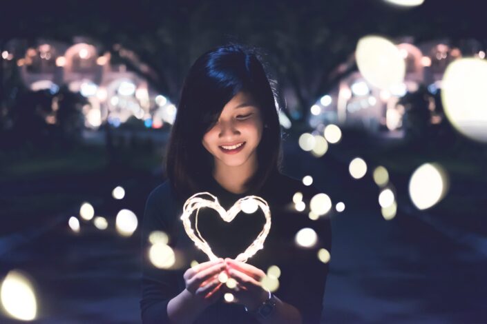 A woman holding heart-shaped lights.