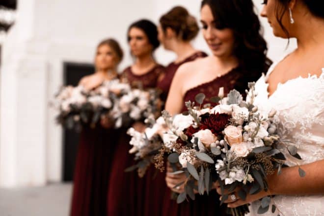 A bride and her bridesmaids holding flowers - Bridesmaid Gifts