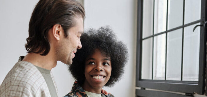 Diverse couple smiling by the window