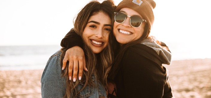 one woman with an arm around another woman's neck smiling