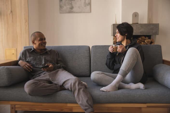 Man and woman comfortably sitting on a couch talking to each other