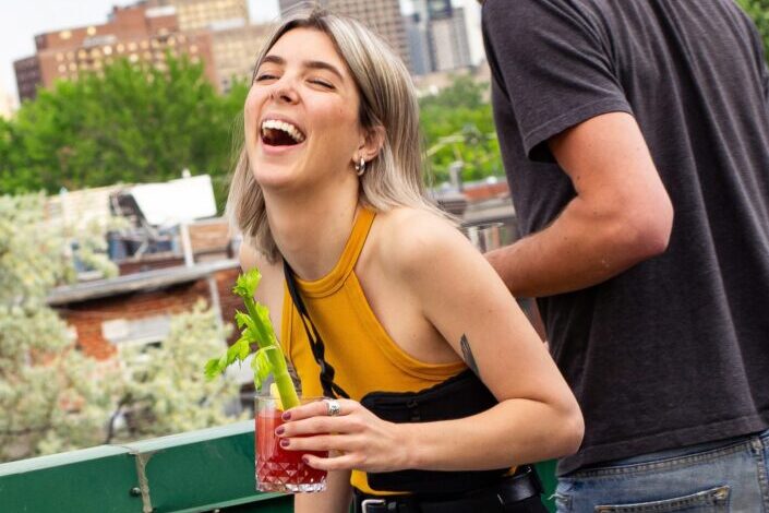 Girl, laughing hard while holding a Bloody Mary drink.