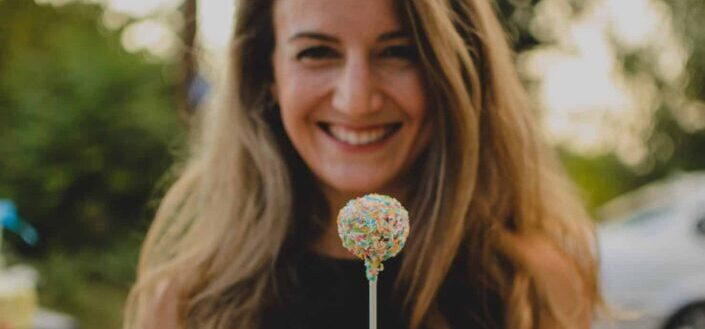 Woman sweetly smiling while holding a candy.