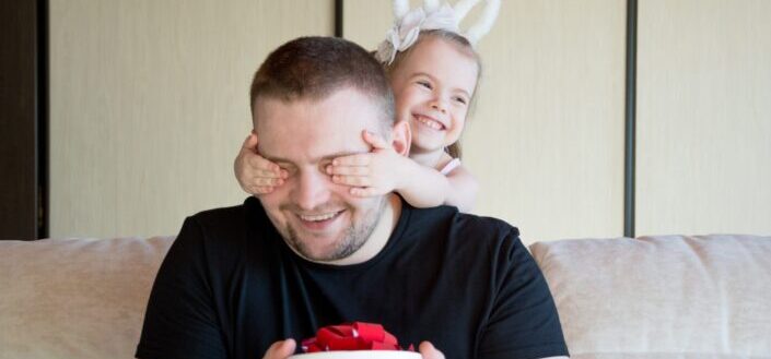 child covering her father's eyes
