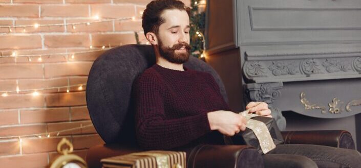 man-sitting-in-armchair-with-christmas-present-
