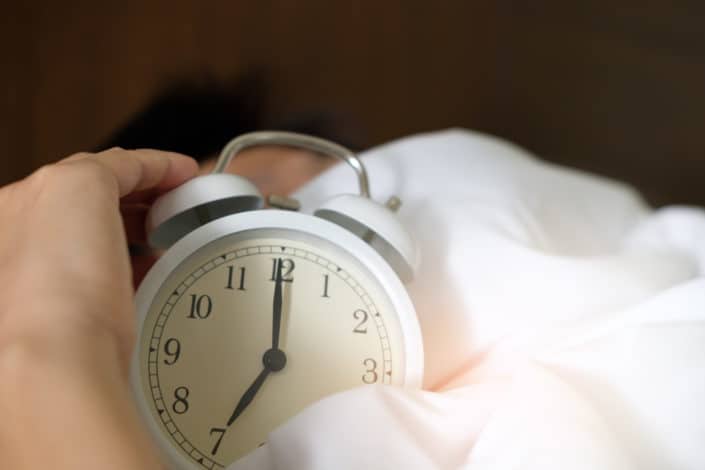 A hand snoozing an alarm clock