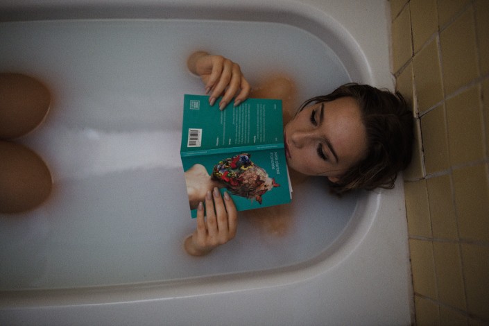 Woman in a bathtub holding a book