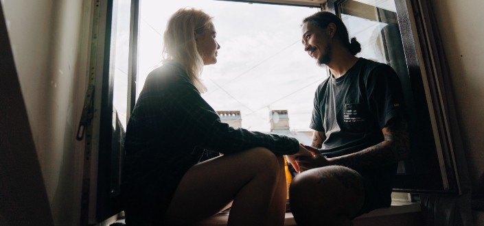 A couple talking to each other by a window