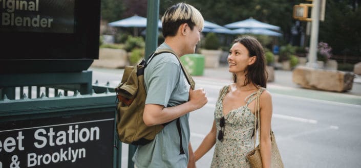 Couple smiling at each other outside subway station sign