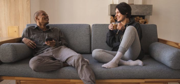 Cozy couple sitting on sofa and drinking coffee