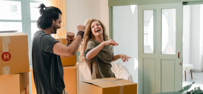 Couple having fun and dancing while unpacking boxes