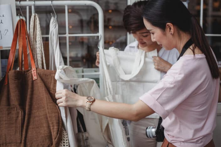 Asian women choosing cotton bags in fashion boutique