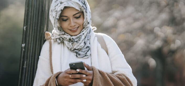 lady wearing hijab amusingly browses her phone