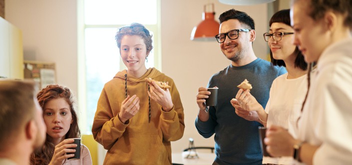 Group of young adults enjoying pizza and a drink.