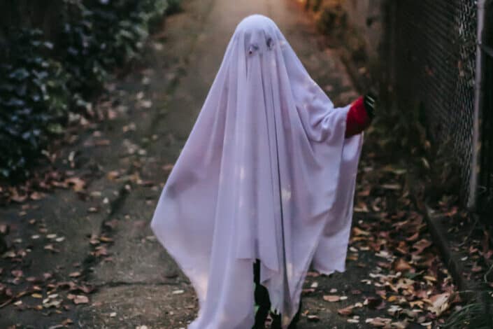 Little girl wearing a white blanket as Halloween costume