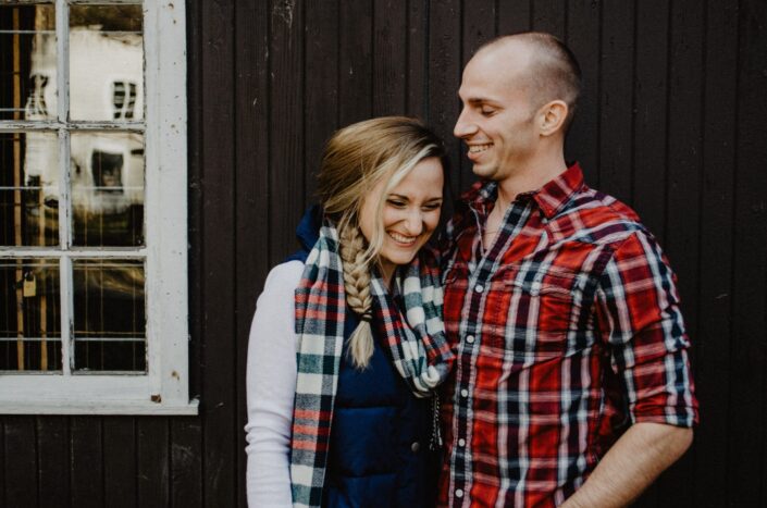 Couple smiling at each other near a window.