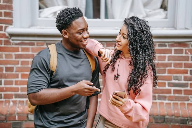 young diverse couple sharing smartphone on street - questions girls are too afraid to ask guys