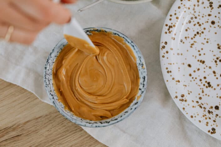 person mixing a peanut butter with a plastic spoon