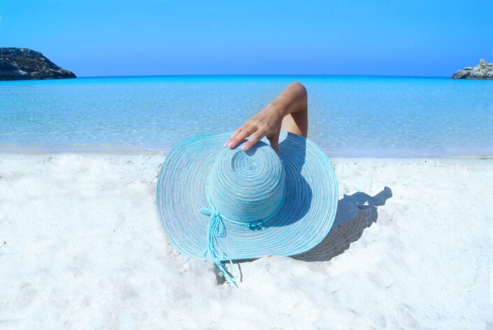 female with a blue hat relaxing at the beach