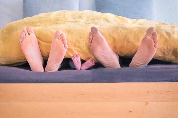 family of three lying in bed