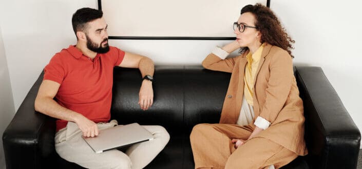 two adults having serious conversation in a couch