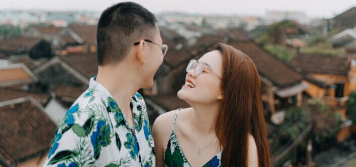 smiling asian couple on balcony under gray sky