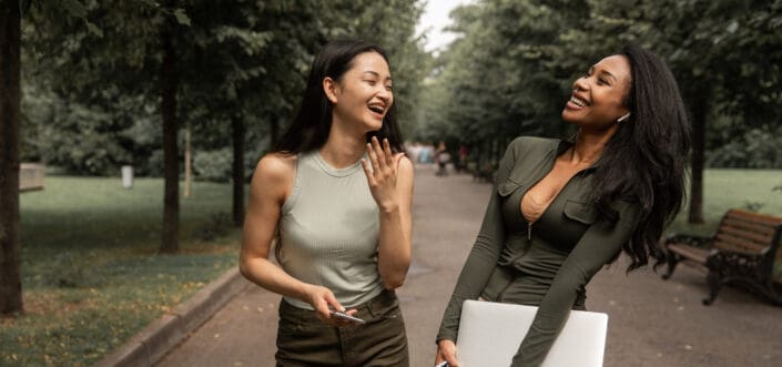 Two female friends laughing while walking.
