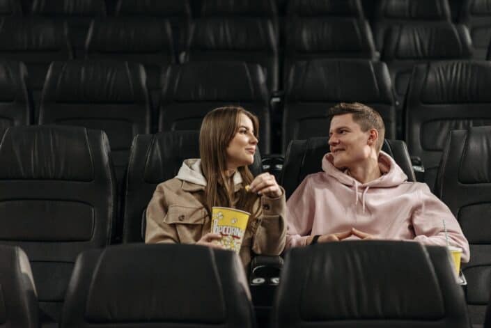 Couple Eating Popcorn while Sitting in Movie Theater