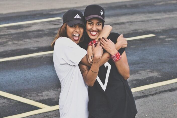 Two happy ladies both wearing caps hugging each other