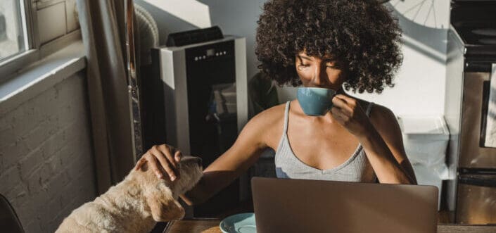 woman drinking coffee while petting her dog