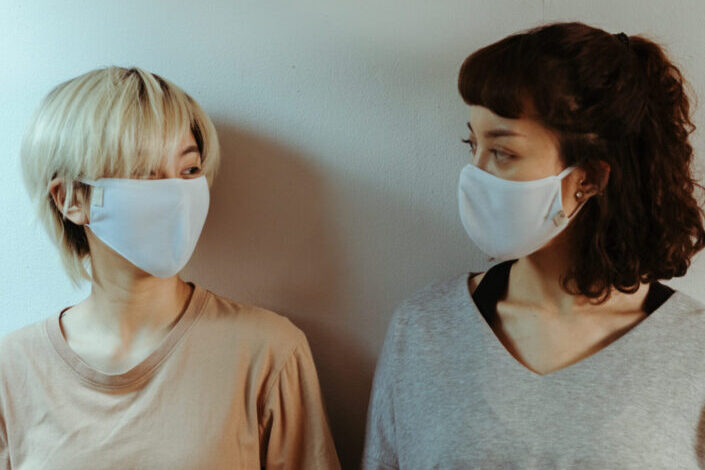 Friends in face masks looking at each other