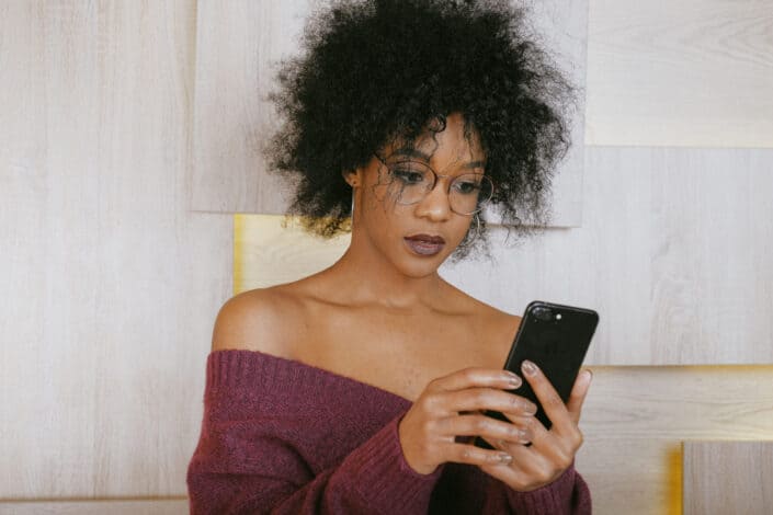 Curly haired lady with cute glasses checking on her phone