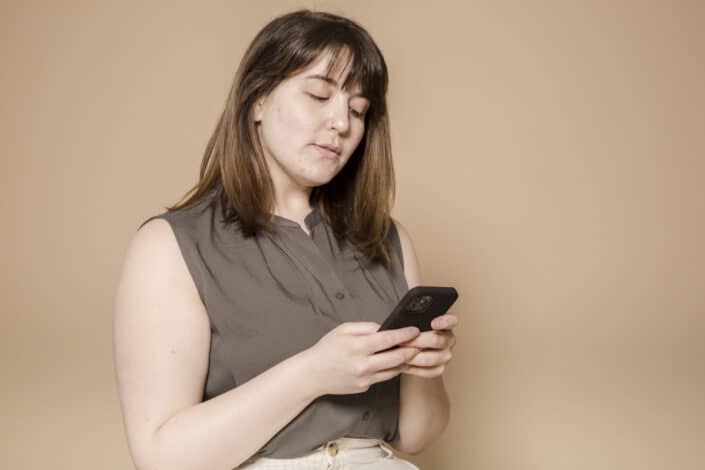 Lady wearing a brown sleeveless blouse checking on her phone