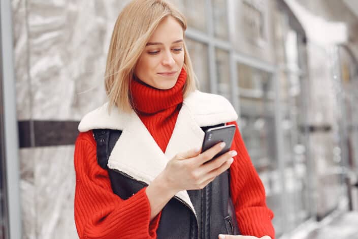 Lady wearing a red outfit smiling over something on her phone