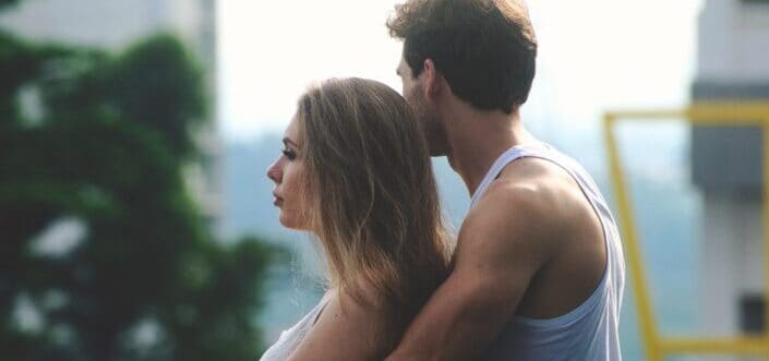 Couple romantically standing on a terrace and looking away.