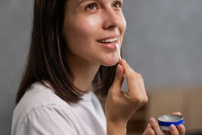 Woman putting on some petroleum jelly on her lip