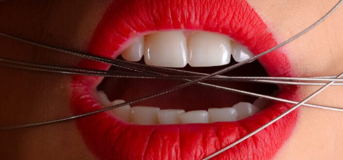 A symbolic photo of red lipped mouth tied with strings