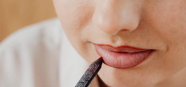 Lady defining her lip shape with a pencil lip liner